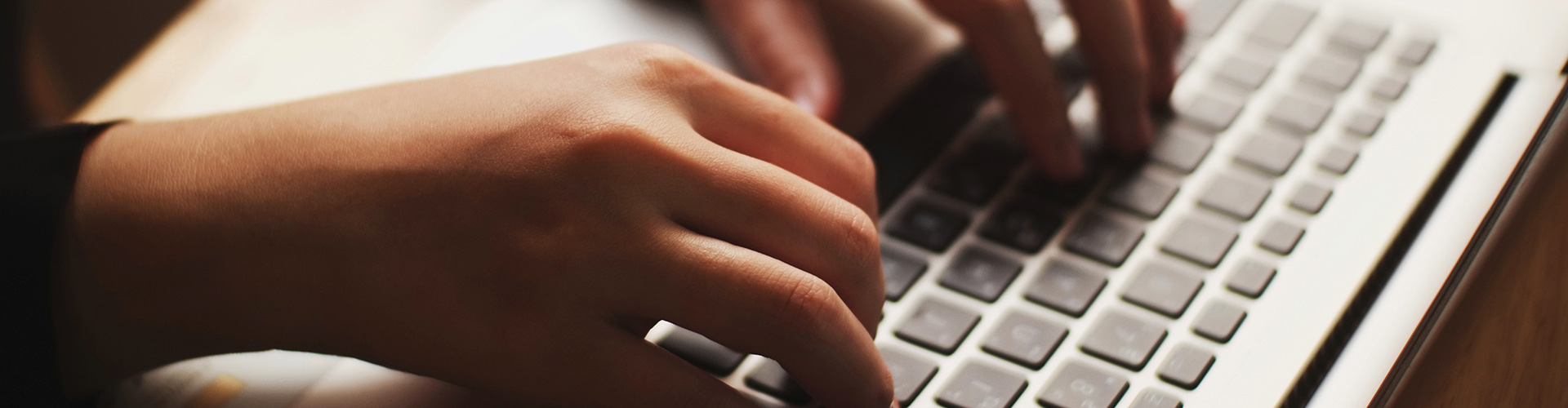 Hands typing on a laptop