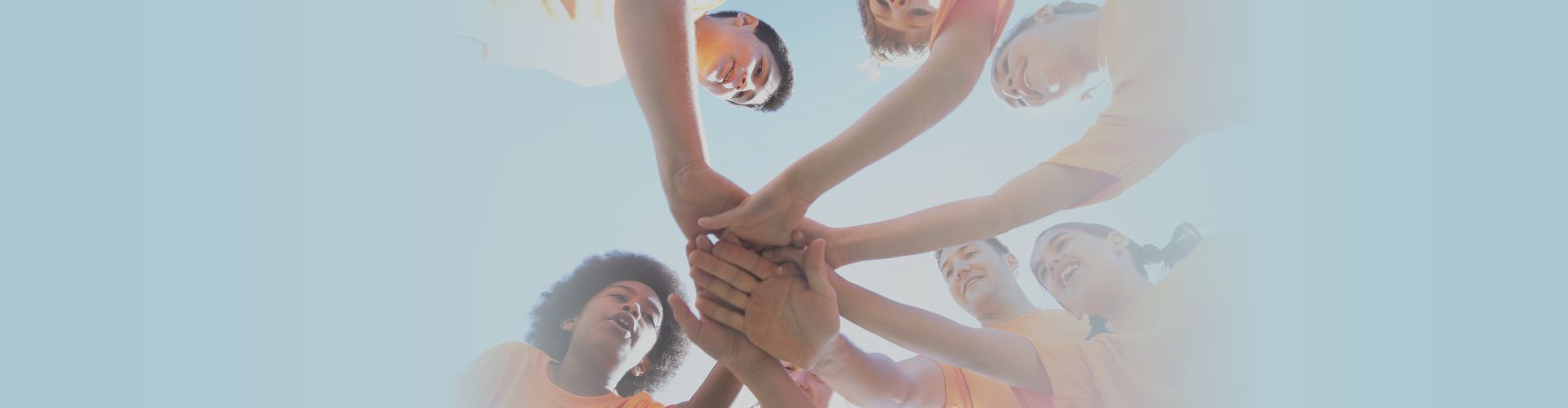 6 young adults standing in circle putting hands together