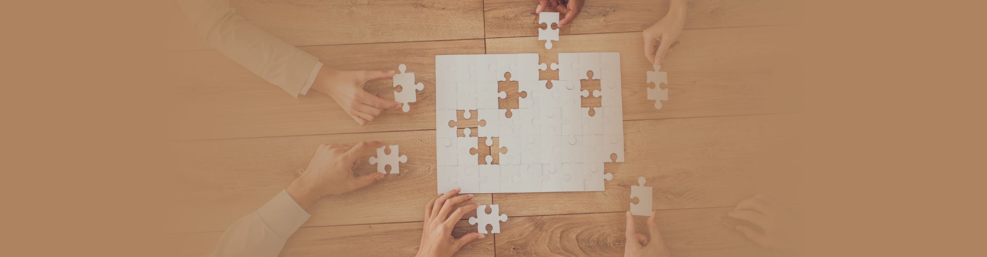 close up of 6 hands working on puzzle