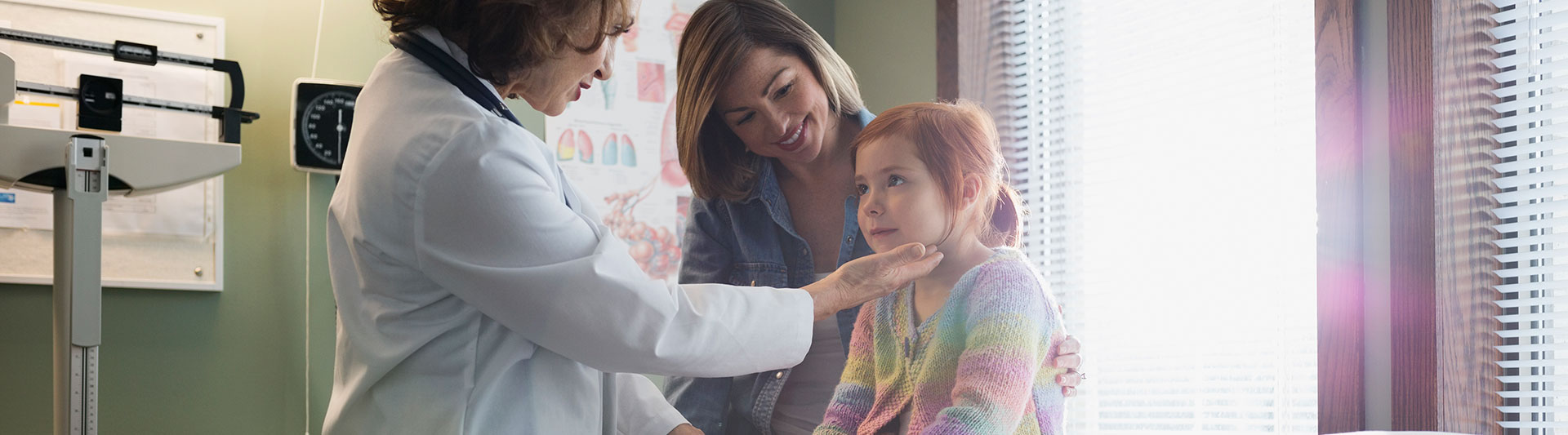 Doctor examining a young patient with her mother